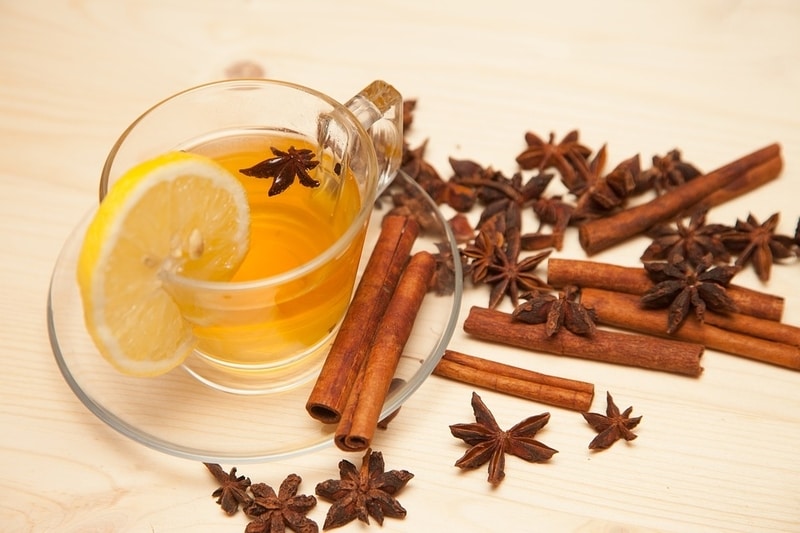 Star anise tea in a cup with star anise pods and cinnamon sticks arrayed around it