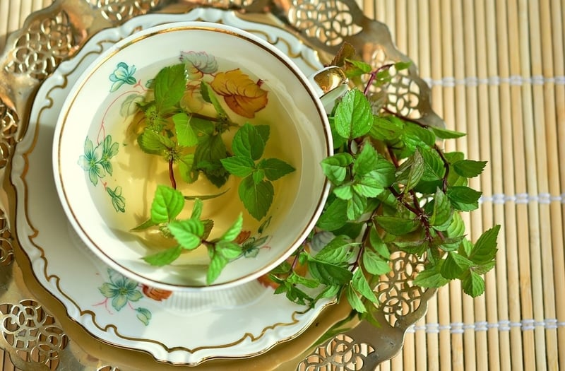 Peppermint tea in fine china with peppermint leaves draped over