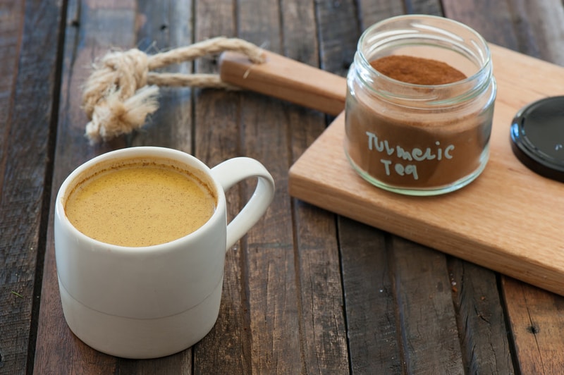 Turmeric tea in a mug and a jar of dried turmeric powder