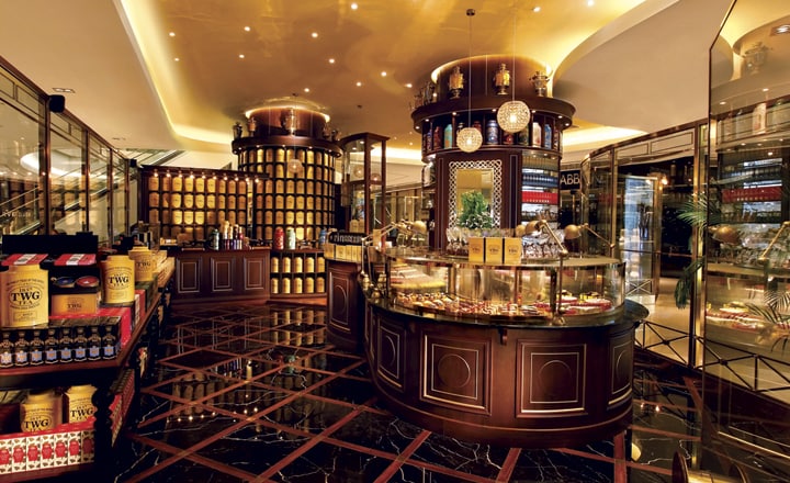 The view inside a TWG tea shop. The design is very luxurious with dim lightning and black floor tiles. Different teas are out on display.